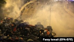 Полиция применяет слезоточивый газ против демонстрантов в Гонконге. 18 ноября 2019 года.