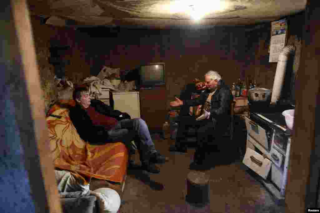 Knezevic talks with a friend in the barn where he has lived for 17 years while waiting for aid to rebuild his old house.