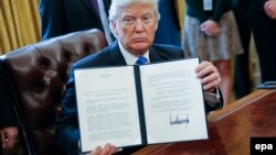 U.S. President Donald Trump holds up one of his recently signed executive orders.