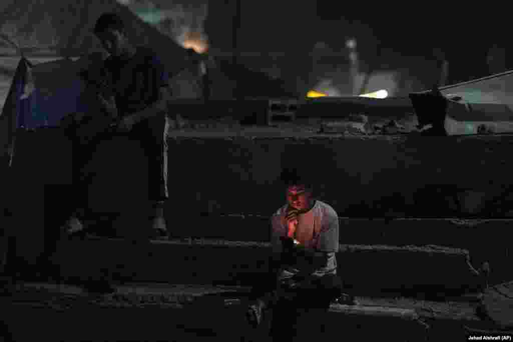 Të rinj palestinezë duke shikuar telefonat e tyre celularë, në një rrugë në Qytetin e Gazës.