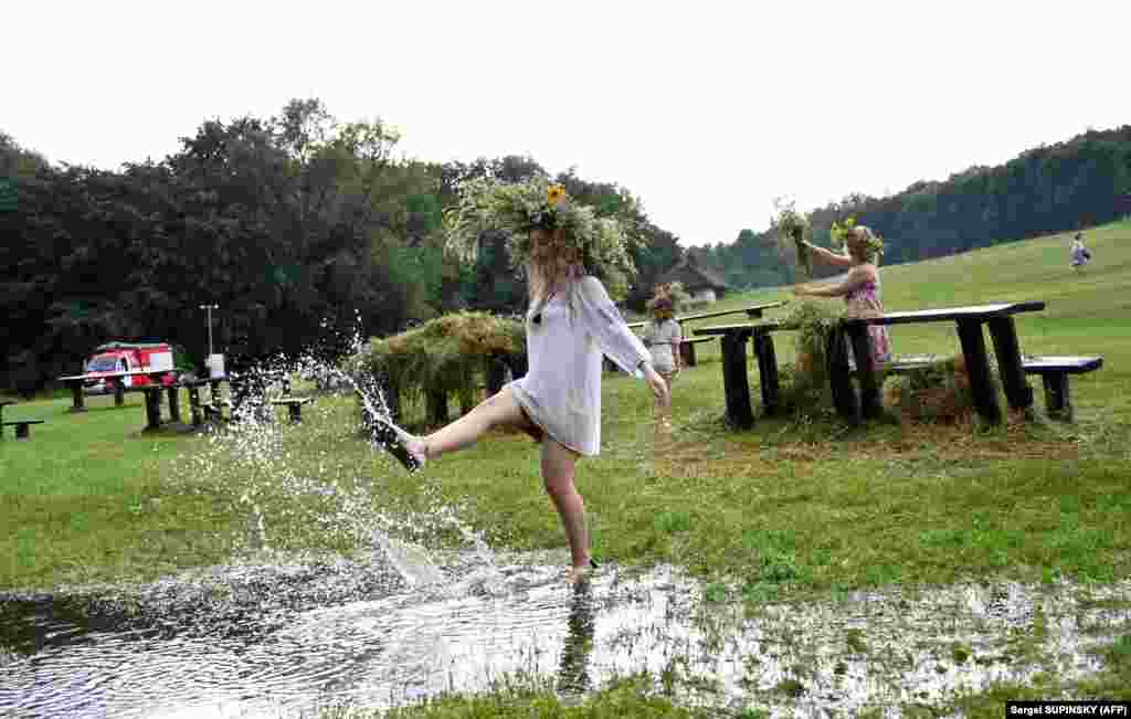 Девушка в традиционной украинской одежде танцует в луже после проливного дождя во время празднования Ивана Купала в Пирогове под Киевом, 6 июля. Во время празднования старинного славянского обряда, посвященного летнему солнцестоянию, люди надевают венки, прыгают через костры, и купаются обнаженными в реках и озерах