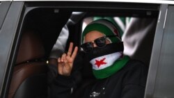 A woman flashes a victory sign as Syrians celebrate a year since the ousting of longtime ruler Bashar al-Assad in Damascus, on December 8