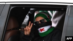 Žena pokazuje znak pobede dok Sirijci 8. decembra u Damasku slave godinu dana od svrgavanja dugogodišnjeg vladara Bašara al-Asada.