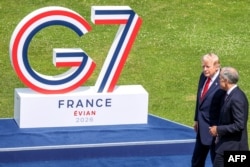 US President Donald Trump (left) and Canadian Prime Minister Mark Carney talk before posing for a family photograph during the G7 summit on June 16.