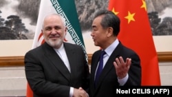 China's Foreign Minister Wang Yi (R) shakes hands with Iran's Foreign Minister Mohammad Javad Zarif during their meeting at the Diaoyutai State Guest House in Beijing on December 31, 2019.