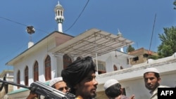 An armed Taliban and residents outside a mosque in the Buner district on April 23