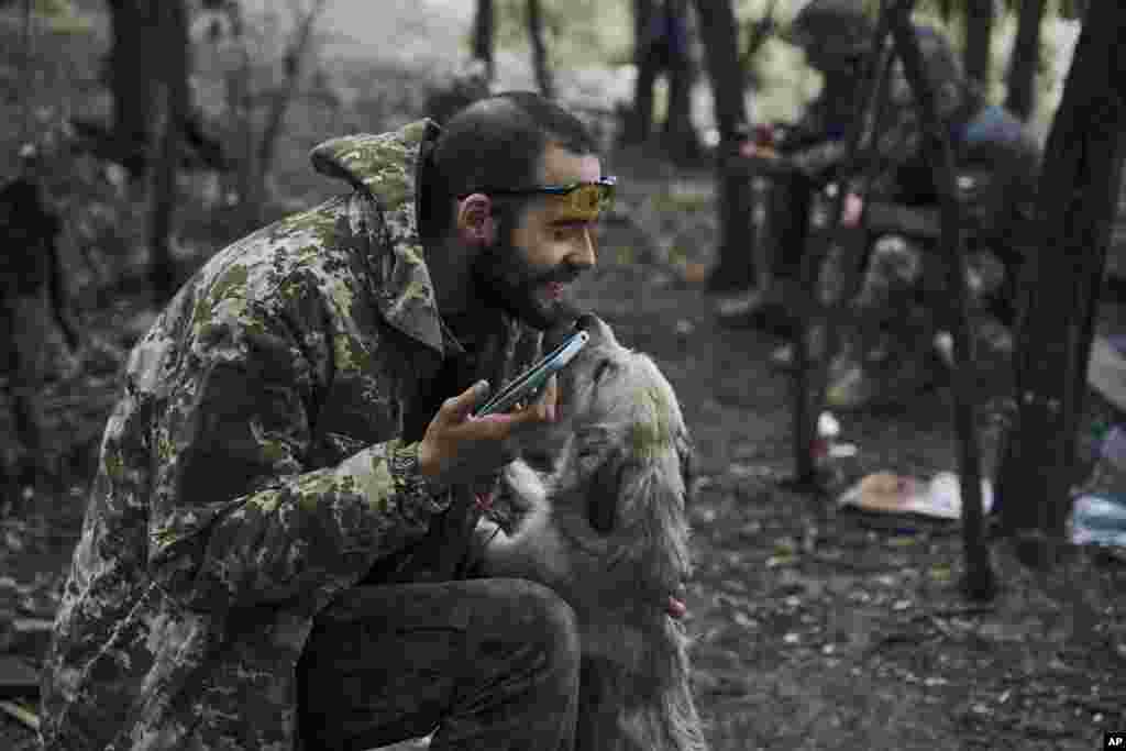 A Ukrainian soldier plays with a dog in liberated territory in the Kharkiv region on September 12, 2022.