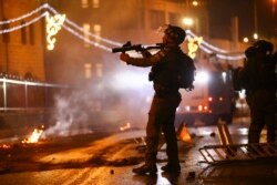 Офицер израильской полиции с направленным на палестинских демонстрантов оружием около Дамасских ворот Старого города в Иерусалиме