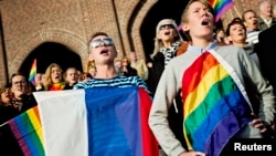 Люди поют российский гимн, держа в руках флаги России и ЛГБТ-сообщества, во время акции протеста против антигейских законов. Стокгольм, 6 октября 2013 года.