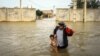 An Iranian man carries his son in a flooded way in a village around the city of Ahvaz, Khuzestan province, March 31, 2019