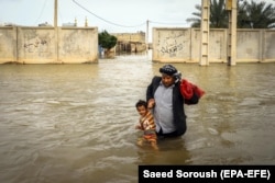 An Iranian man carries his son in the flooded city of Ahvaz on March 31.