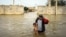 An Iranian man carries his son in a flooded way in a village around the city of Ahvaz, Khuzestan province, March 31, 2019