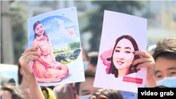 Protesters hold up pictures of Aizada Kanatbekova at a demonstration in Bishkek after her death.