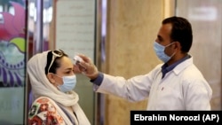 IRAN -- A woman wearing a protective face mask to help prevent spread of the coronavirus has her temperature checked as she enters a shopping center, in Tehran, August 19, 2020