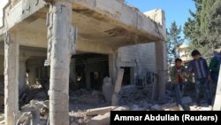 Луѓе ги согледуваат штетите од воздушните напади во област која е под контрола на бунтовниците во градот Алепо. 