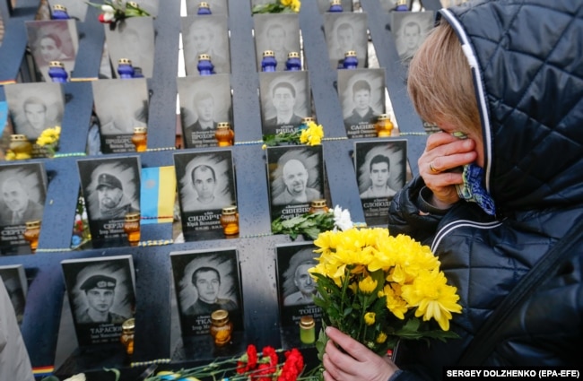 Девушка приносит цветы к мемориалу на Аллее героев небесной сотни в Киеве