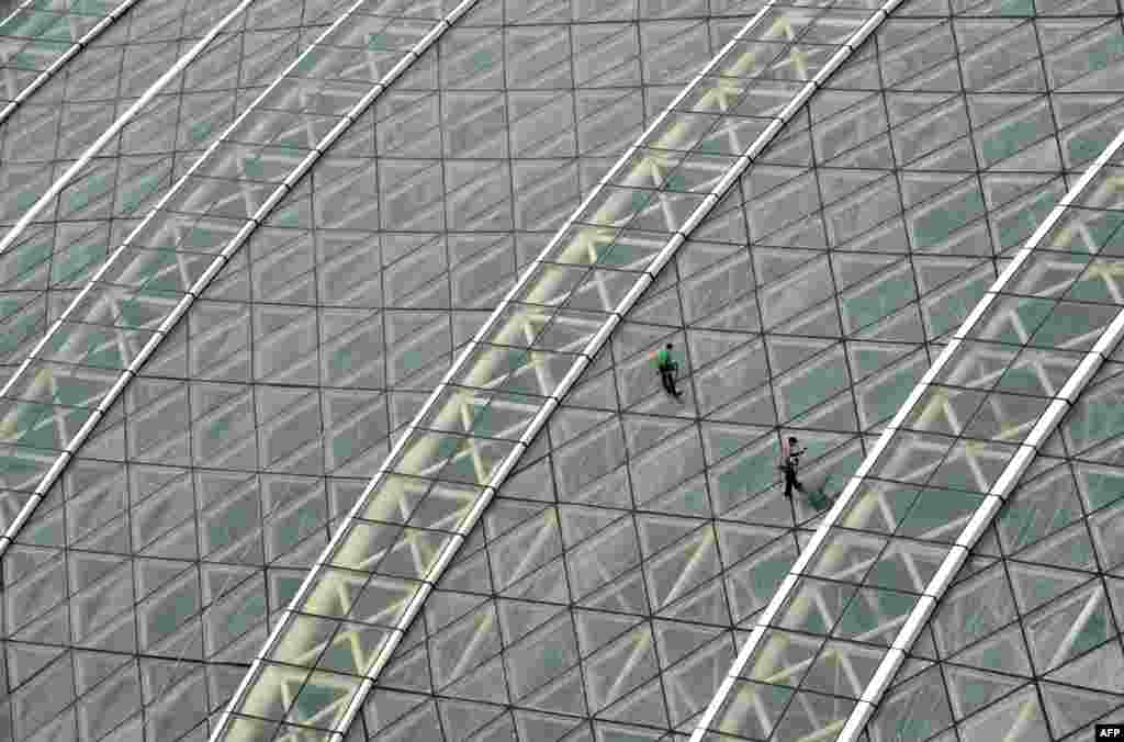 Workers clean the glass roof of the massive structure. With 1.7 million square meters of floor space, the center could house Washington&#39;s Pentagon Building three times over.