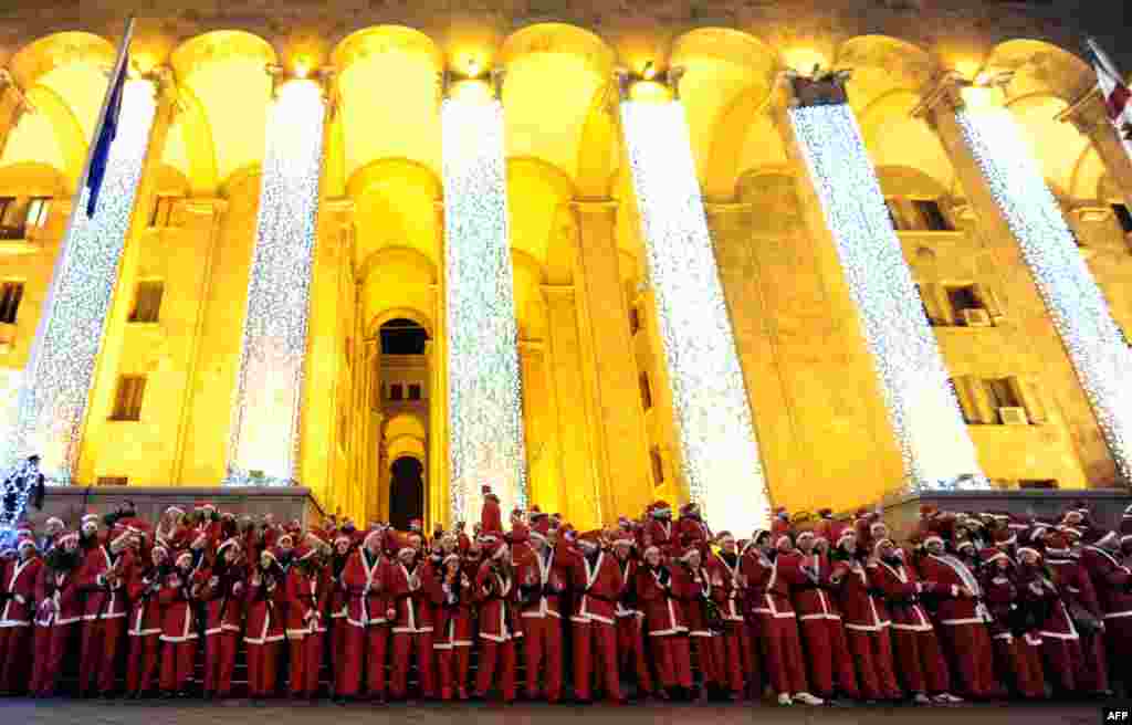 People dressed as Santa Claus perform near a New Year&#39;s tree in front of the Georgian parliament building in Tbilisi. (AFP/Vano Shlamov)