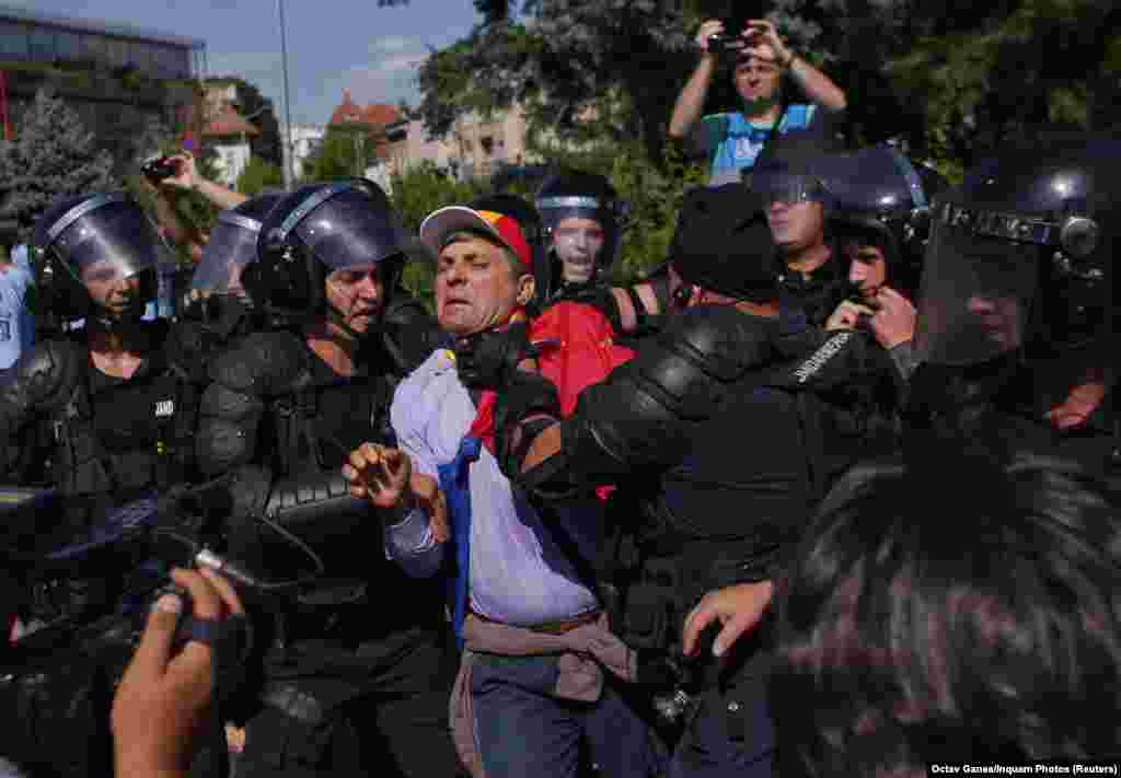 Police officers hold a man as thousands of Romanians hold rallies in major cities across the country and outside government headquarters in the capital, Bucharest, on August 10. (Reuters)