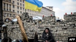 Участник антиправительственного протеста сидит у баррикады в центре Киева. 24 февраля 2014 года.