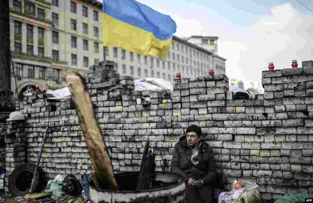 An antigovernment protestor sits behind a barricade on Kiev's Independence Square. (AFP/Bulent Kiric)