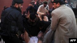 Пакистанские полицейские уносят мертвое тело своего коллеги. Иллюстративное фото. Пешавар, 24 февраля 2012 года.