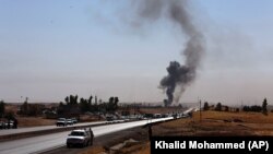 Smoke rises as Kurdish security forces withdraw from a checkpoint in Alton Kupri, on the outskirts of Irbil, on October 20.