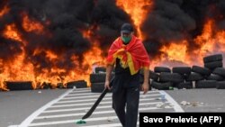 Muškarac pored zapaljenih guma na barikadi postavljenoj kako bi blokirala put na Cetinje tokom protesta protiv ustoličenja mitropolita Joanikija, 5. septembra 2021. godine