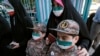 An Iranian mother and her children, wearing Islamic Revolutionary Guards Corps uniforms, line up at a polling station to cast her vote for the presidential election on June 18.