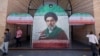 Commuters walk past a tiled image of current leader Ayatollah Mojtaba Khamenei near a Tehran subway station on May 9. 