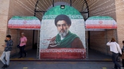 Commuters walk past a tiled image of current leader Ayatollah Mojtaba Khamenei near a Tehran subway station on May 9. 