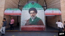 Commuters walk past a tiled image of current leader Ayatollah Mojtaba Khamenei near a Tehran metro station on May 9. 