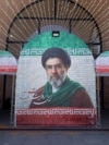 Këmbësorë ecin pranë një imazhi të liderit aktual të Iranit, ajatollahut Mojtaba Khamenei, pranë një stacioni metroje në Teheran, më 9 maj.