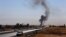 Smoke rises as Kurdish security forces withdraw from a checkpoint in Alton Kupri, outside of Irbil, on October 20.