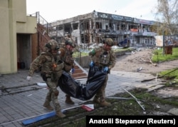 Поліцейські з «Білого янгола» несуть тіло жертви російського обстрілу, Покровськ, 12 квітня 2025 року