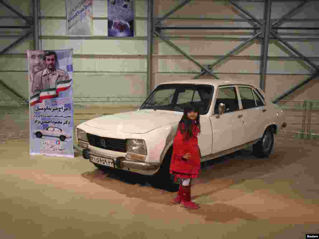 A girl poses next to Iran President Mahmud Ahmadinejad's 1977 Peugeot 504, which was auctioned for charity. Photo by Mohammadreza Dehdari for Reuters