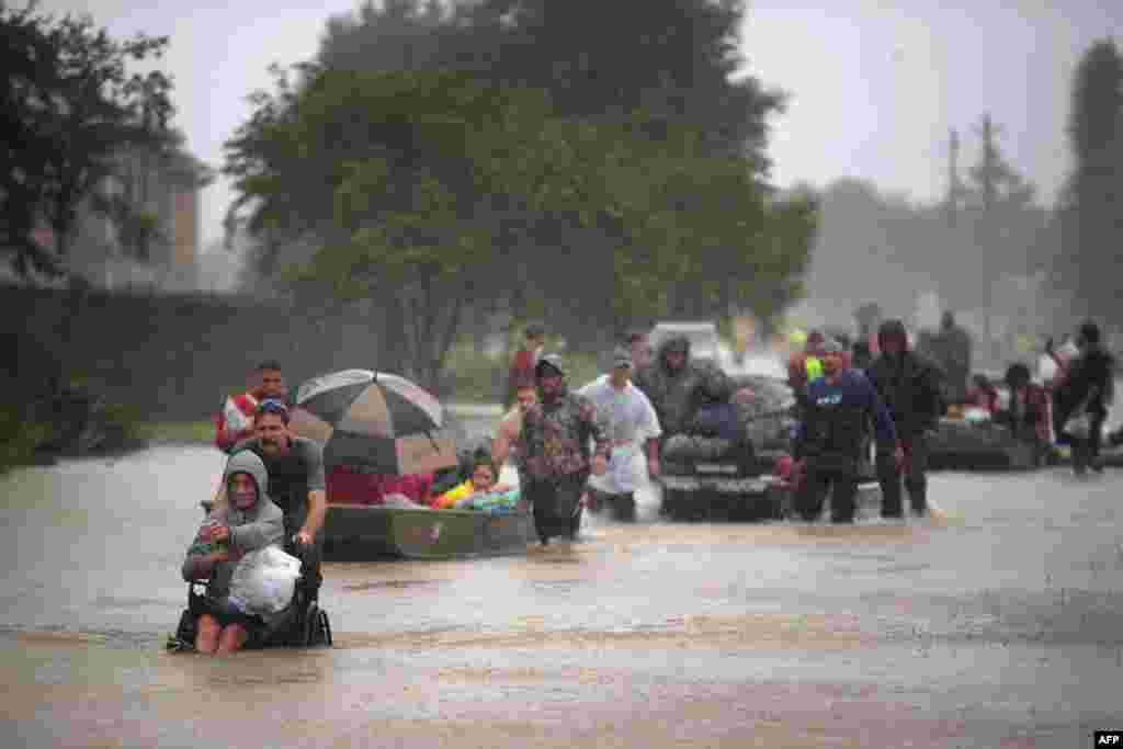 People flee a flooded Houston neighborhood following Hurricane Harvey. A record 75 centimeters of rain has fallen in Houston, the fourth-largest city in the United States, since Harvey made landfall as a Category 4 hurricane on August 25, bringing massive flooding. Harvey has been blamed for at least three confirmed deaths and tens of thousands of people have been driven from their homes.&nbsp;(AFP/Scott Olson/Getty Images)