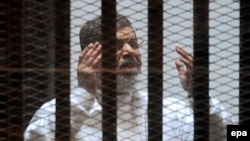 Ousted Egyptian President Muhammad Morsi gestures in a cage during a court hearing in Cairo in 2015. 