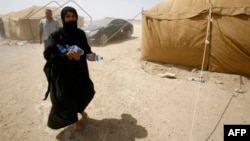 A displaced Iraqi woman who fled Anbar Province due to the ongoing conflict between pro-government forces and Islamic State militants carries bottles of water at a makeshift camp for internally displaced persons some 30 kilometers south of Fallujah on May 25.