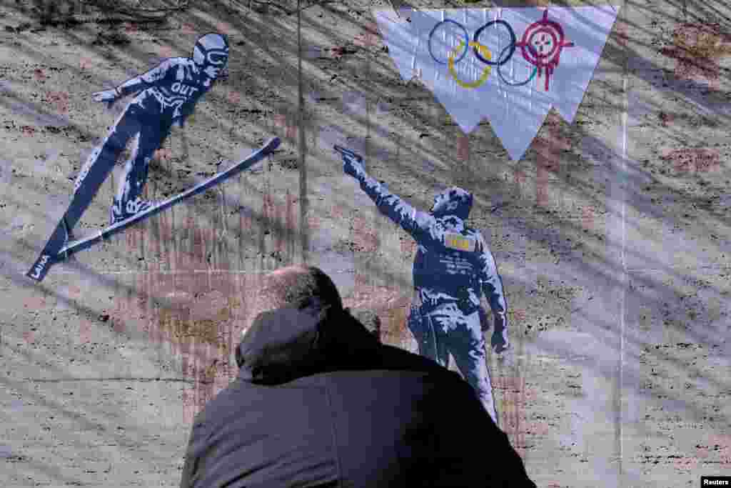 Представитель СМИ снимает на камеру мурал художника Лайки, изображающую сотрудника ICE, нацелившегося на прыгуна с трамплина, Рим, Италия, 5 февраля 2026 года. REUTERS/Remo Casilli