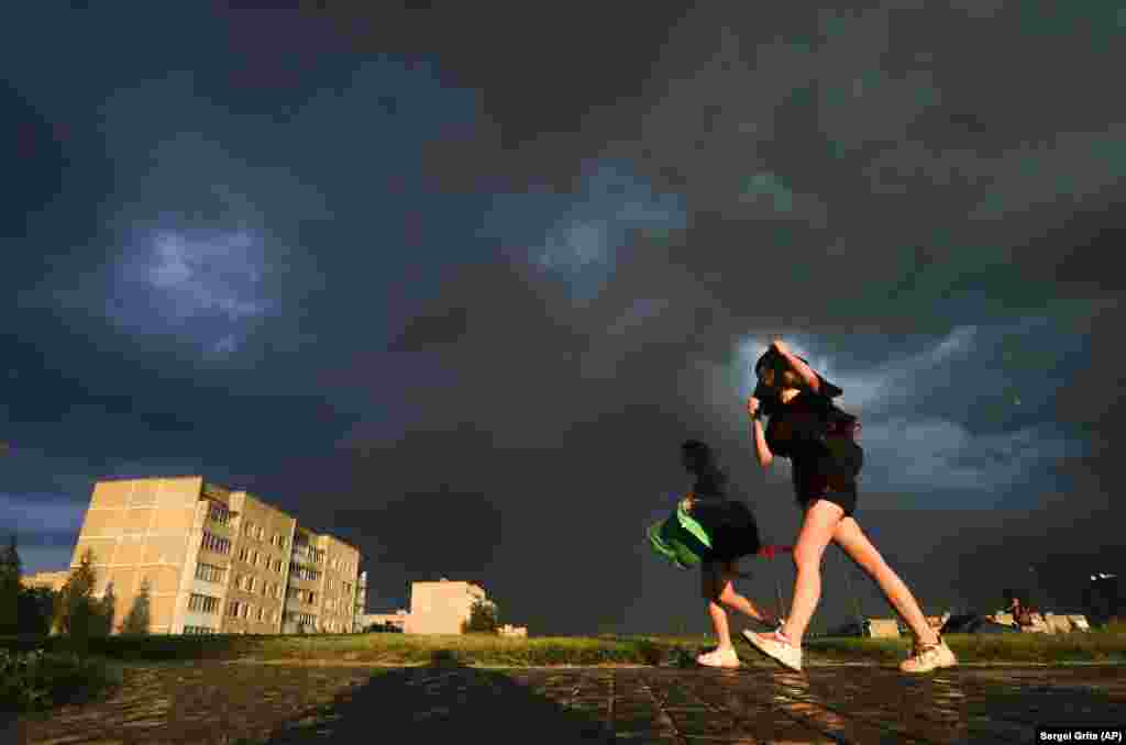 Girls brave strong winds as storm clouds roll above the the town of Novogrudok, 150 kilometers west of Minsk on June 18, minutes before heavy rain engulfed the city. (AP/Sergei Grits)​