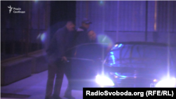 Охоронець, який погрожував зброєю журналістам, відчиняє двері авто російському бізнесмену Павлу Фуксу
