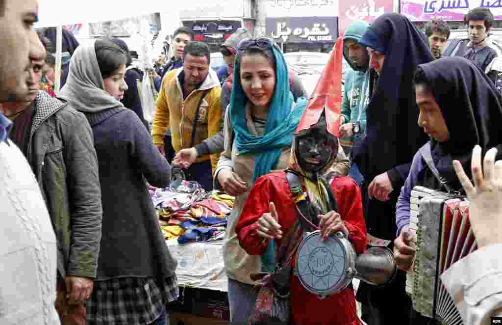 An Iranian girl plays music dressed as Haji Firouz, a Norouz tradition in Tehran.