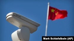 Kínai zászlót lenget a szél egy térfigyelő kamera mögött Pekingben 2019. október 8-án