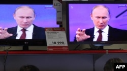 Russia -- Customers stand next to the TV screens during the broadcast of Prime Minister Vladimir Putin's annual phone-in session with Russians in Moscow, 15Dec2011