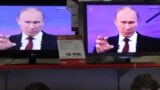 Russia -- Customers stand next to the TV screens during the broadcast of Prime Minister Vladimir Putin's annual phone-in session with Russians in Moscow, 15Dec2011