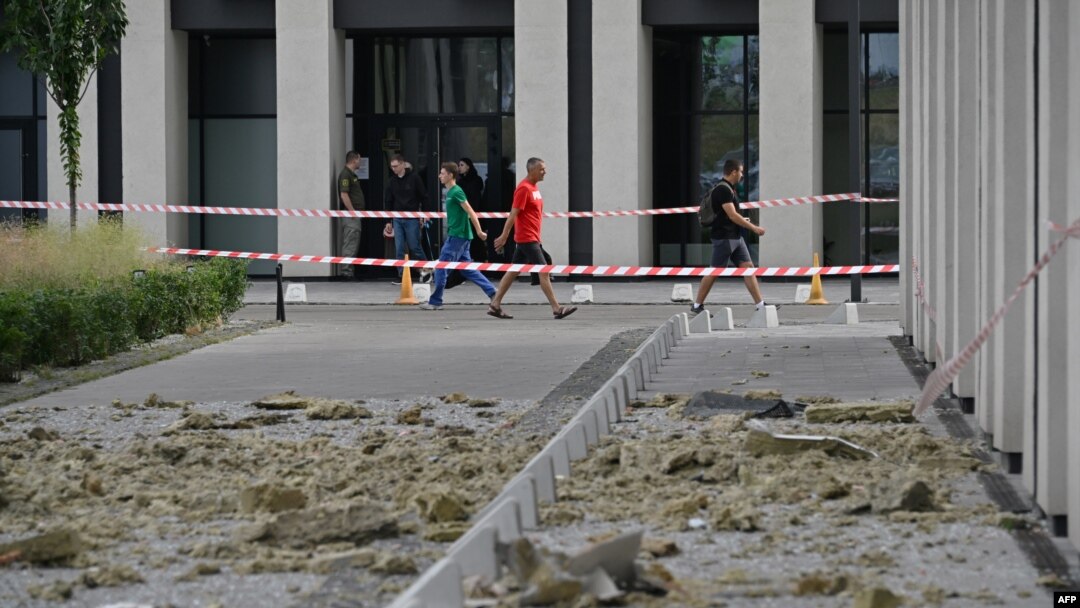 People walk past a high-rise residential building damaged by the remains of a downed Russian drone in Kyiv on July 13. 