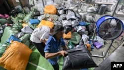 Muncitori într-un depozit al companiei de curierat internațional Weijiang, care se ocupă de coletele Temu, în Guangzhou, China, pe 12 august 2025.