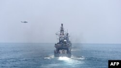 A helicopter flies over a US navy vessel during a joint military exercise between Qatar and the US navy, in Doha, June 16, 2017