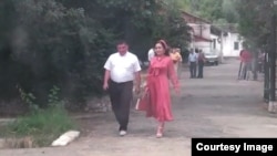 Асан Мансуров и Самара Каримова выходят из здания, где располагается ошский городской офис партии «Биримдик».